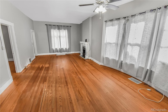 unfurnished living room with ceiling fan, a wealth of natural light, and hardwood / wood-style flooring