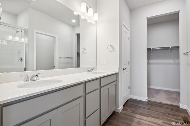 1321 Loraine Cir N, Lafayette, CO 80026 - bathroom featuring a sink, a spacious closet, a shower stall, and wood finished floors
