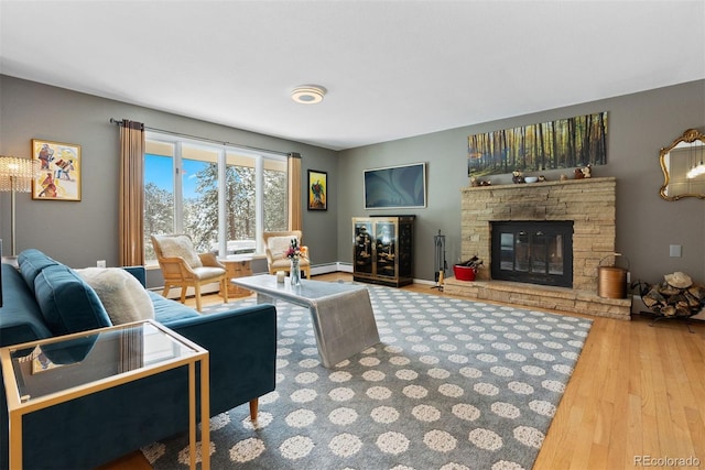 living area with a baseboard heating unit, a fireplace, wood finished floors, baseboards, and baseboard heating