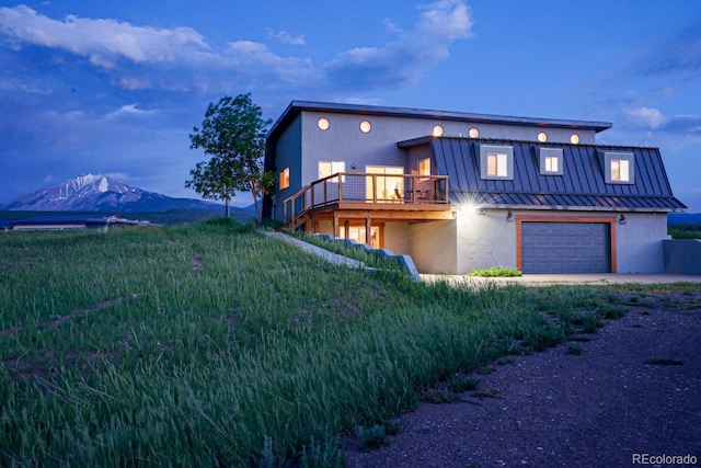 view of front of property featuring a garage, a front yard, and a deck with mountain view