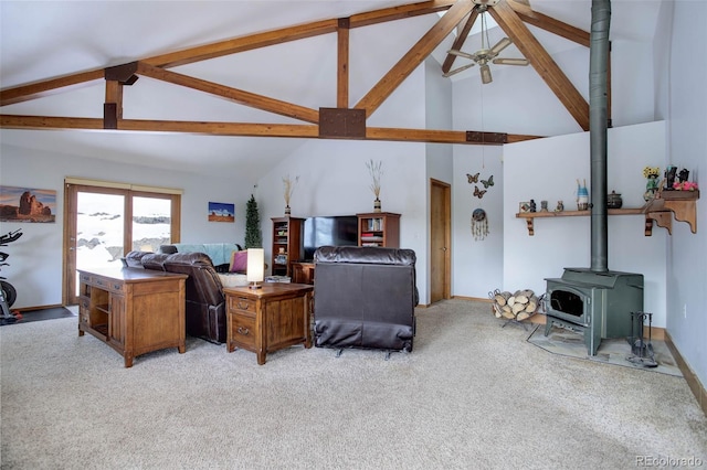 living room featuring ceiling fan, beam ceiling, high vaulted ceiling, light colored carpet, and a wood stove