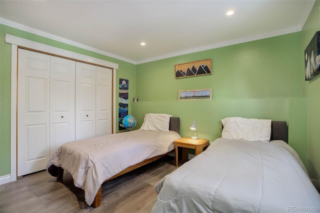 bedroom with ornamental molding, light hardwood / wood-style floors, and a closet