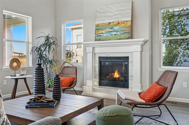sitting room with a wealth of natural light, baseboards, a tiled fireplace, and wood finished floors