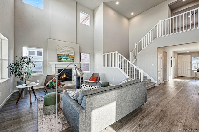 living area featuring a healthy amount of sunlight, dark wood finished floors, and a towering ceiling
