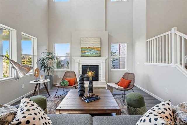 living room featuring a high ceiling, baseboards, a tile fireplace, and wood finished floors