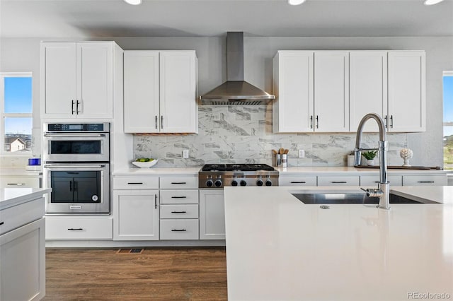 kitchen with recessed lighting, wall chimney exhaust hood, stainless steel appliances, and a sink