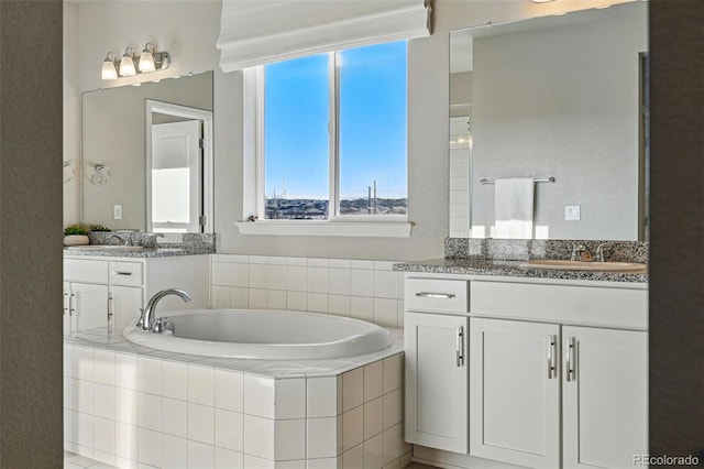 full bath with a bath, two vanities, and a sink