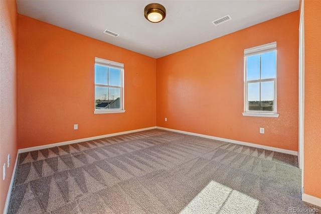 spare room featuring carpet, visible vents, baseboards, and a healthy amount of sunlight