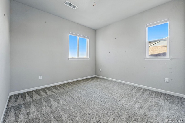 empty room with baseboards, visible vents, and carpet