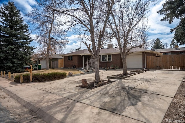 single story home with concrete driveway, brick siding, an attached garage, and fence