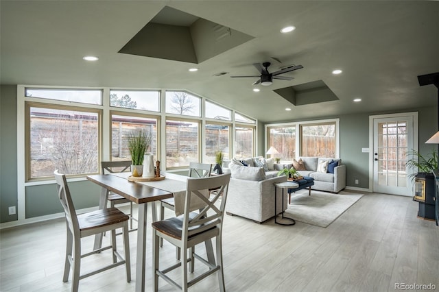 sunroom featuring lofted ceiling, visible vents, a wood stove, and a ceiling fan