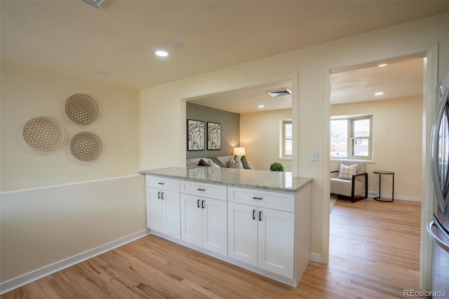 kitchen with visible vents, baseboards, white cabinetry, light stone countertops, and light wood finished floors