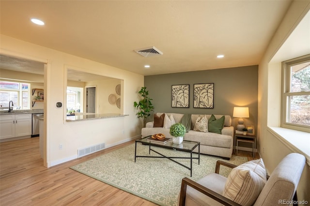 living area with plenty of natural light, visible vents, and light wood-style flooring