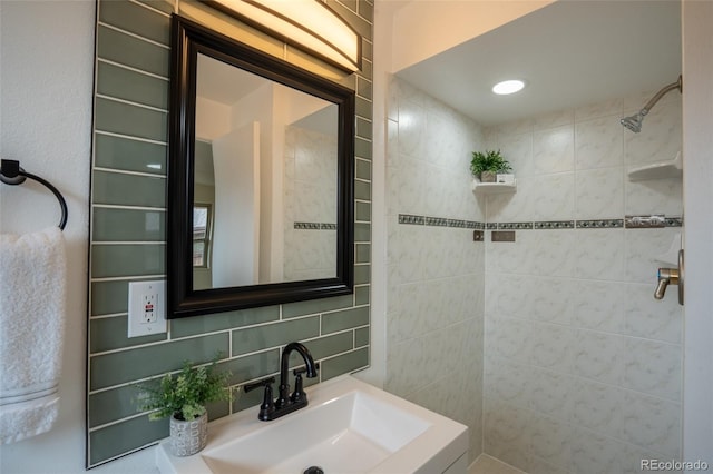 bathroom with tiled shower, backsplash, and a sink