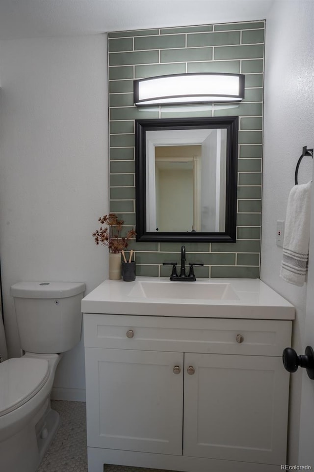 bathroom with tasteful backsplash, baseboards, vanity, and toilet