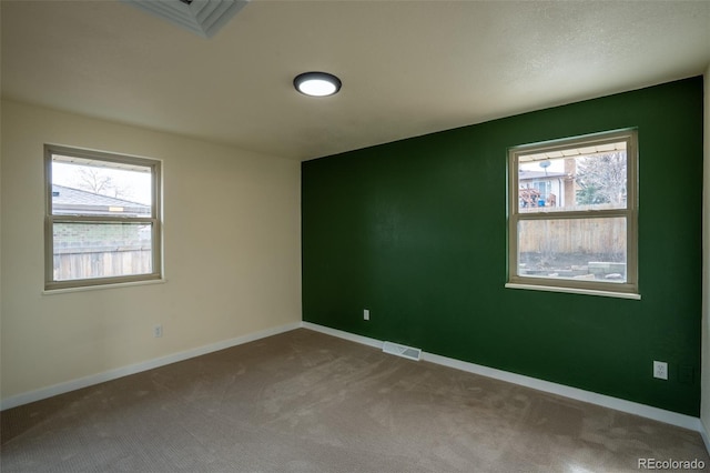 unfurnished room with carpet floors, baseboards, and visible vents