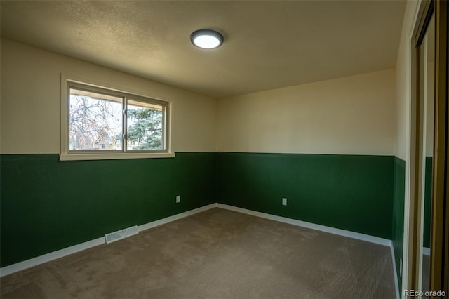 carpeted empty room featuring visible vents and baseboards