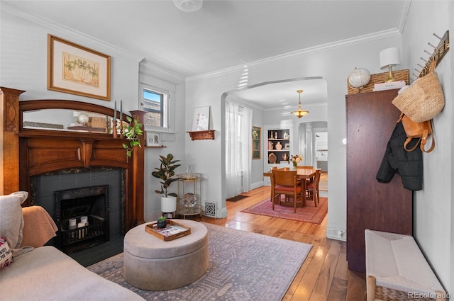 living room featuring a tiled fireplace, wood-type flooring, and crown molding