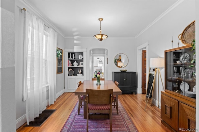 dining space with crown molding, a wealth of natural light, and light hardwood / wood-style floors