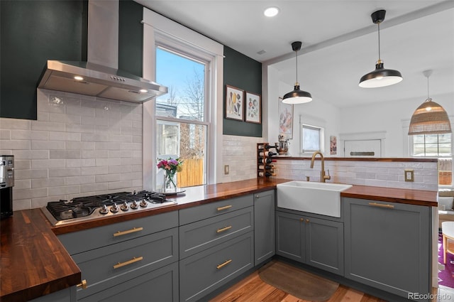 kitchen featuring sink, wooden counters, wall chimney exhaust hood, and stainless steel gas cooktop