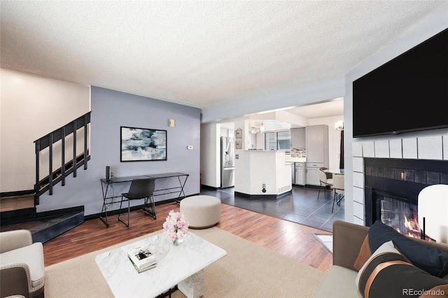 living room with a tiled fireplace, a textured ceiling, and dark hardwood / wood-style floors