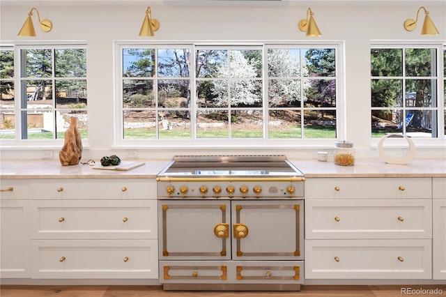 kitchen featuring a wealth of natural light, white cabinetry, and light stone counters