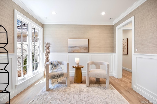 living area with wallpapered walls, wood finished floors, and crown molding