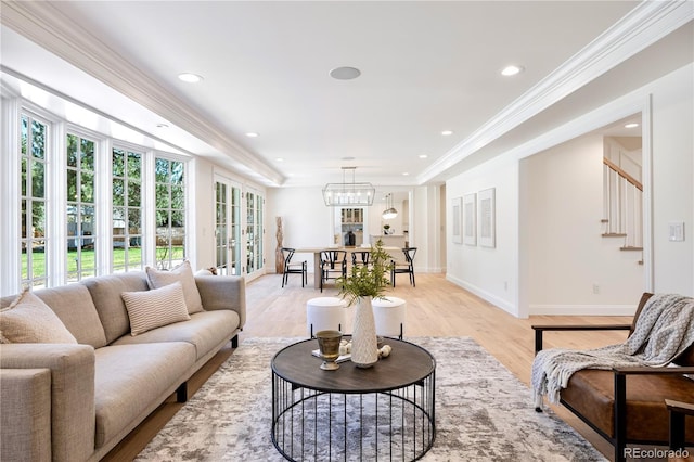living area with light wood finished floors, baseboards, a notable chandelier, stairway, and crown molding
