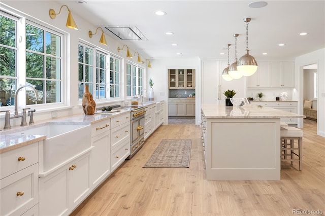 kitchen featuring white cabinets, plenty of natural light, a center island, and a sink