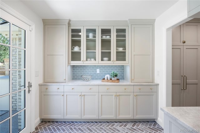 bar with decorative backsplash, baseboards, and brick floor