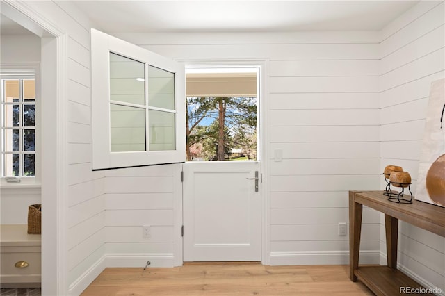 doorway featuring light wood finished floors and wooden walls
