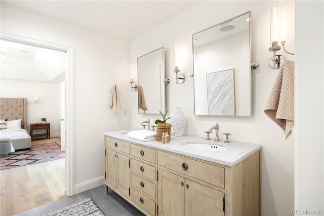 bathroom featuring double vanity, baseboards, ensuite bathroom, and a sink