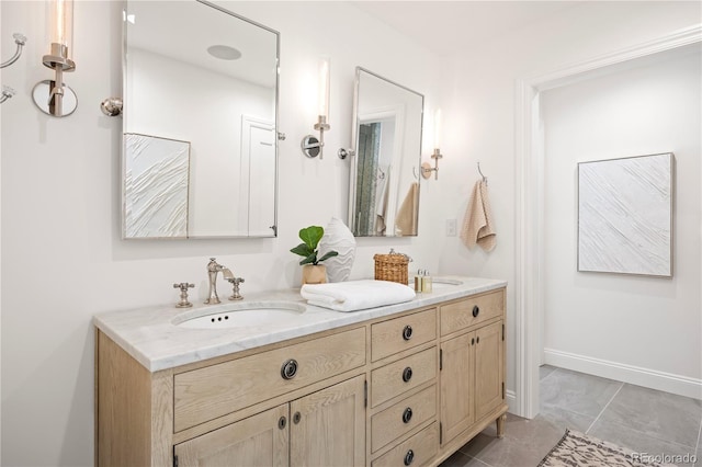 full bath with double vanity, baseboards, and a sink