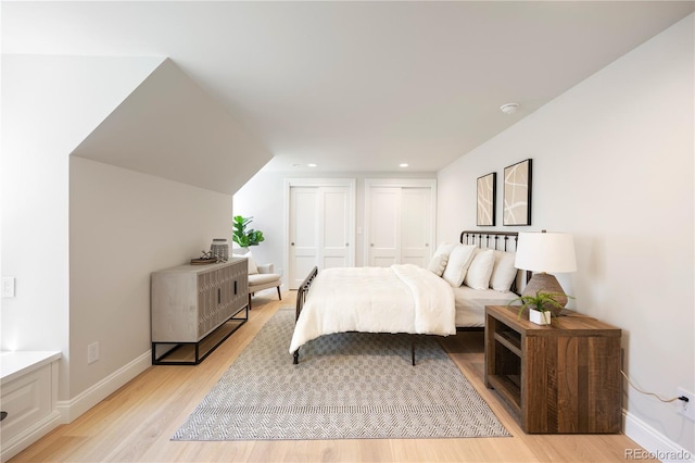 bedroom featuring recessed lighting, baseboards, multiple closets, and light wood-style flooring