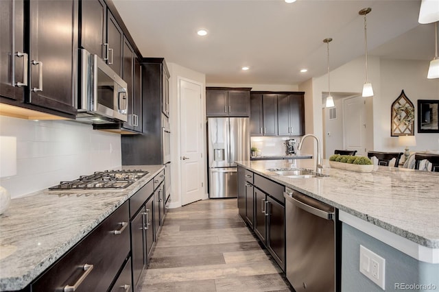 kitchen featuring stainless steel appliances, a center island with sink, sink, and pendant lighting