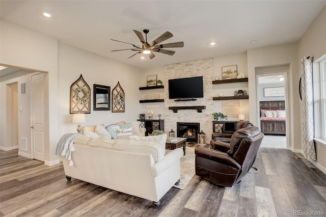 living room featuring ceiling fan, a fireplace, and dark hardwood / wood-style flooring