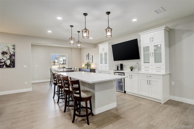 kitchen with white cabinetry, a kitchen island, sink, and wine cooler