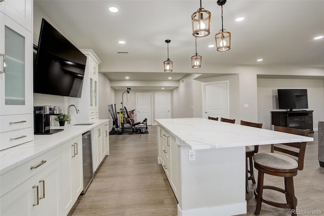 kitchen featuring pendant lighting, sink, a kitchen breakfast bar, a center island, and white cabinets