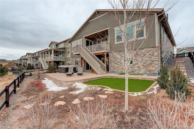 rear view of property featuring a hot tub and a patio area