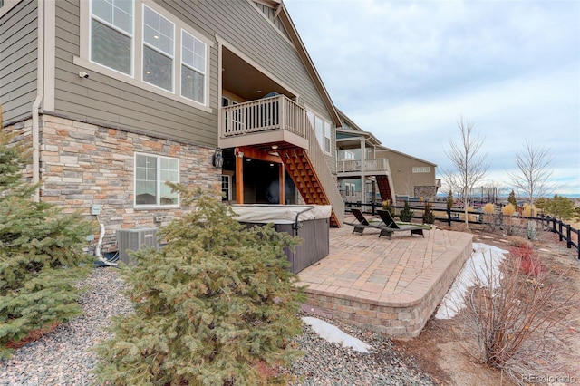 back of property with central AC unit, a patio area, and a hot tub