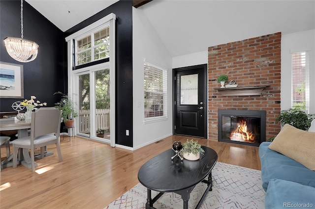 2021 S Hannibal Way Unit F, Aurora, CO 80013 - living area featuring high vaulted ceiling, wood finished floors, a chandelier, a fireplace, and plenty of natural light