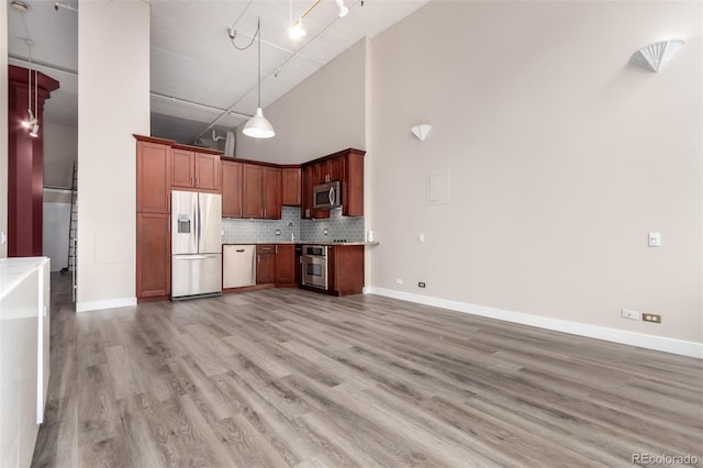 720 16th St Unit 207, Denver, CO 80202 - kitchen with stainless steel appliances, a towering ceiling, light countertops, backsplash, and decorative light fixtures