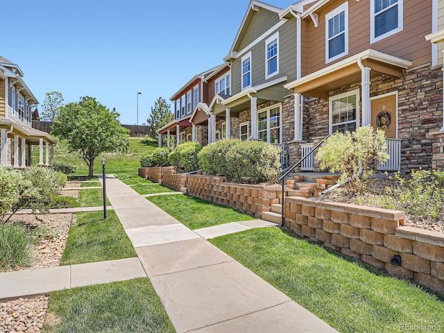 13638 Garfield St Unit C, Thornton, CO 80602 - view of side of home with stone siding, a porch, and a lawn