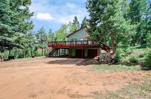 1625 Sand Rd, Woodland Park, CO 80863 - view of front of home featuring stairway, a wooden deck, dirt driveway, and a garage