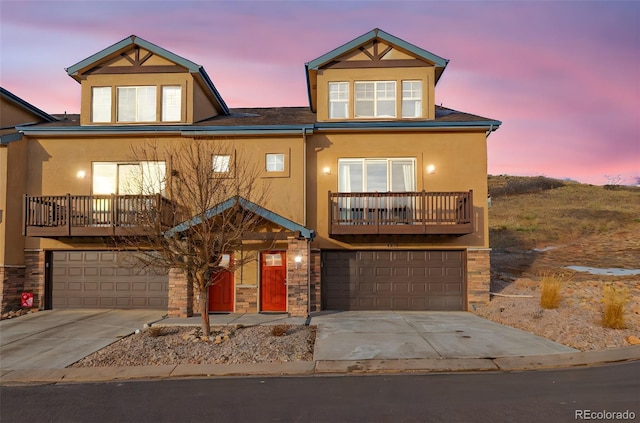 view of front of home with an attached garage, a balcony, driveway, and stucco siding