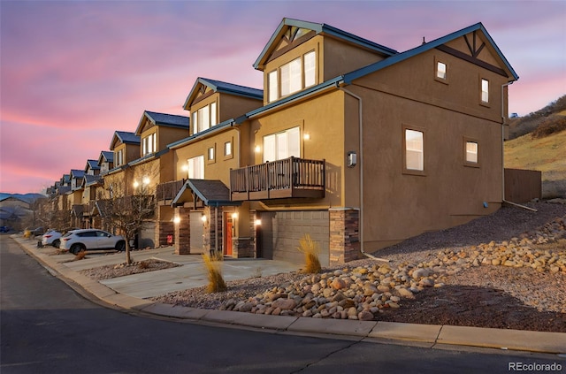 view of front of house with concrete driveway, a residential view, a balcony, stucco siding, and an attached garage