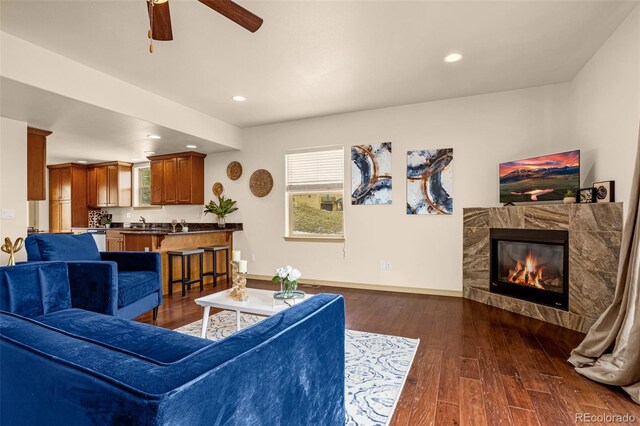 living room with baseboards, dark wood-style flooring, a ceiling fan, recessed lighting, and a tile fireplace
