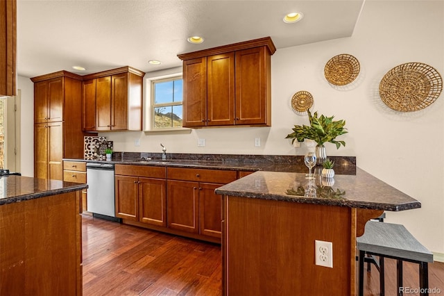kitchen with stainless steel dishwasher, dark wood-type flooring, a peninsula, a kitchen bar, and recessed lighting