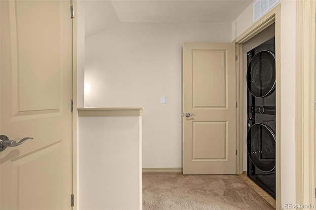 washroom featuring stacked washing maching and dryer, laundry area, light carpet, and visible vents