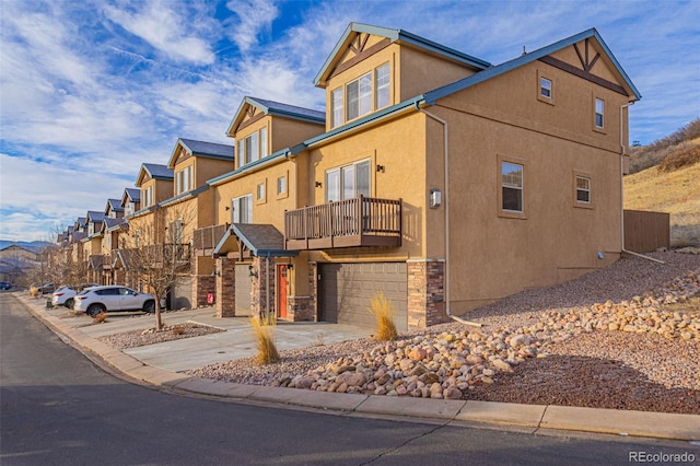 exterior space with a residential view, stucco siding, a balcony, driveway, and a garage